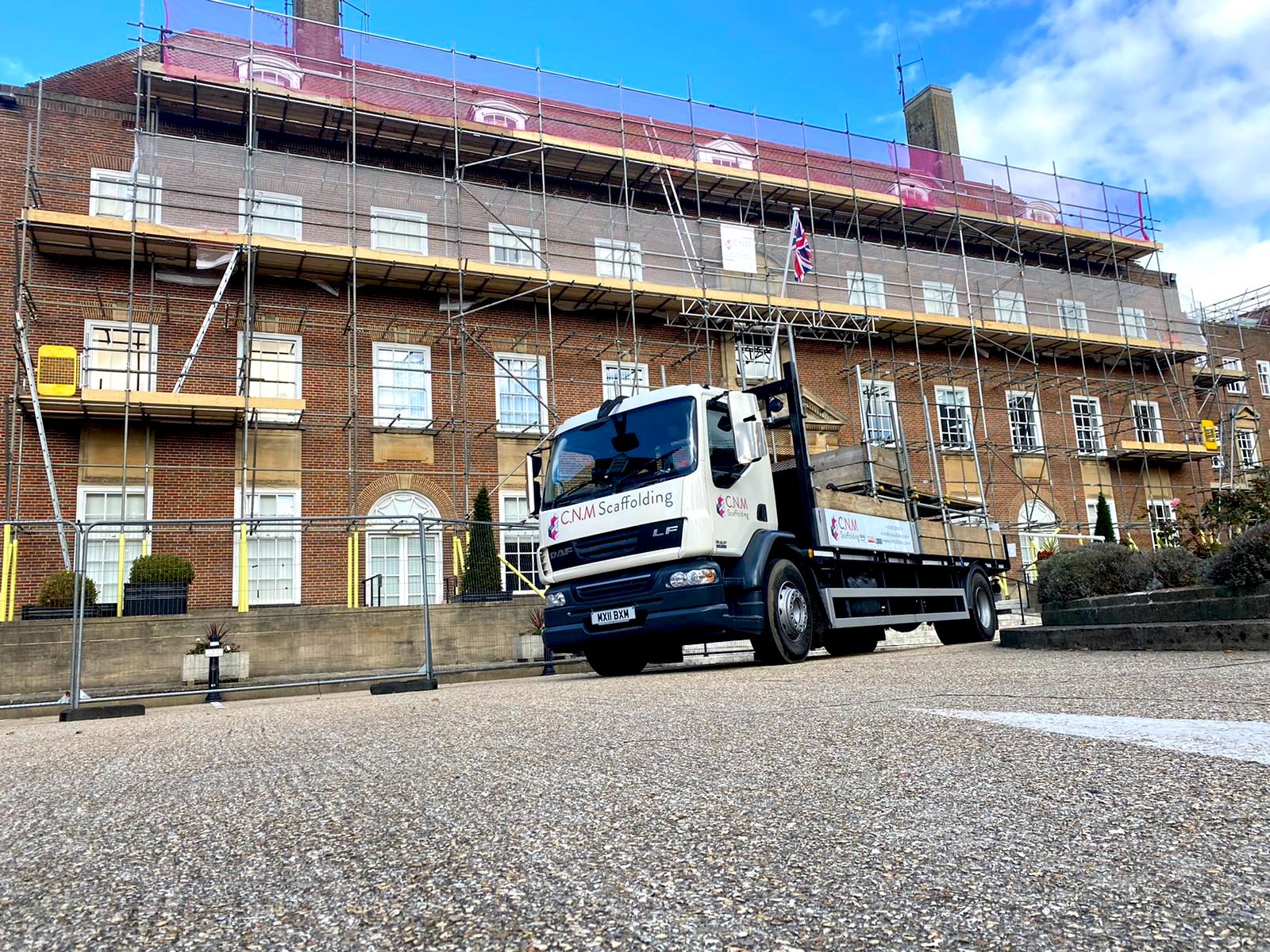 Large building with scaffolding with van outside